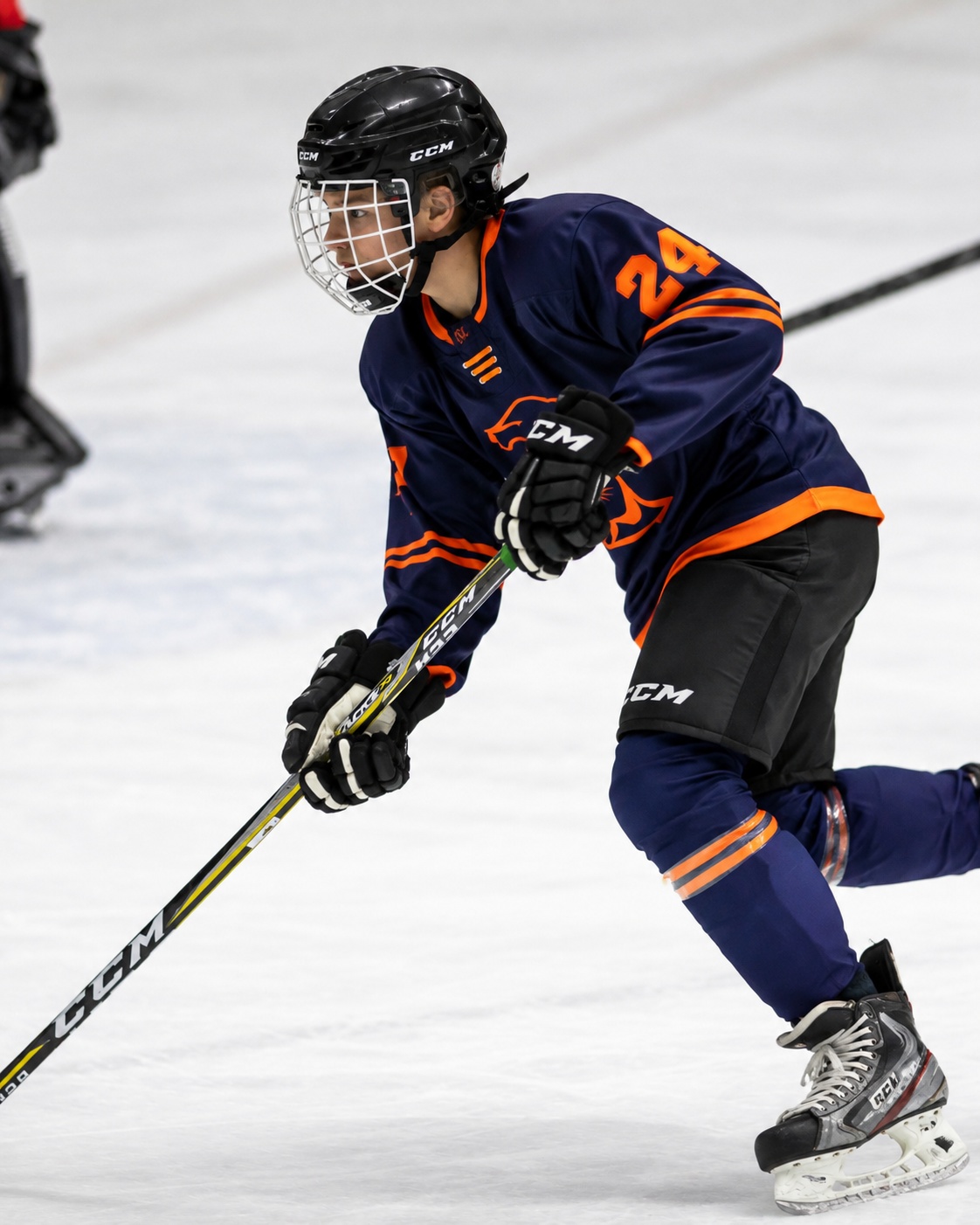 Jeune joueur de hockey en chandail bleu et blanc tenant son bâton sur la glace